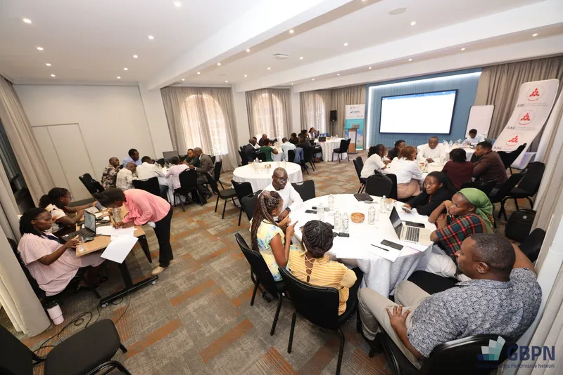 Participants working at round tables during the workshop, with AAK banners and a screen at the front